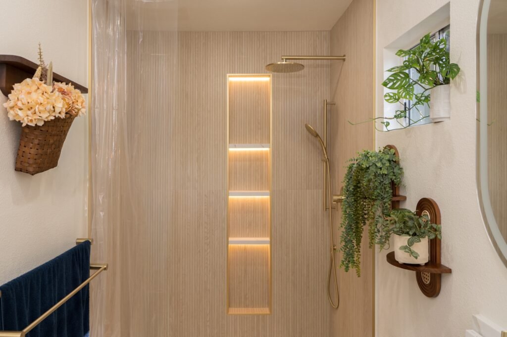 Walk-in shower with a four-shelf backlit niche, brass rain head and hanging plants