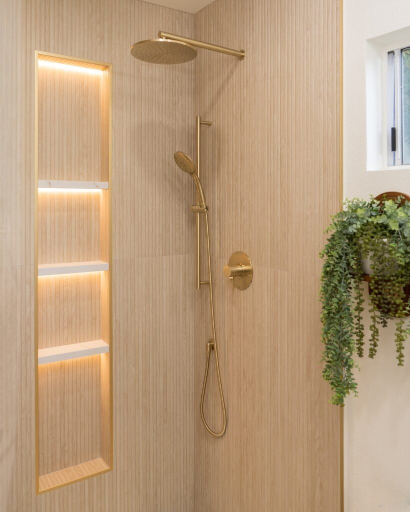 Shower corner with a backlit niche, handheld slide bar, brass mixer and frosted window